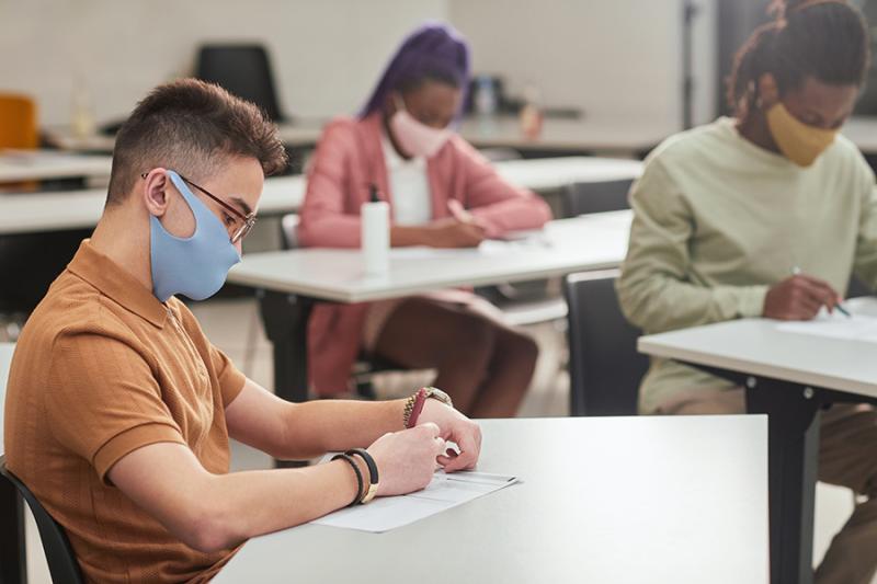 students in a classroom wearing masks and writing