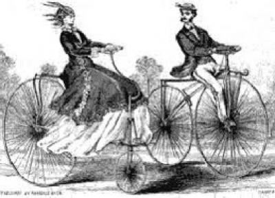 a man and a woman riding old fashioned bicycles